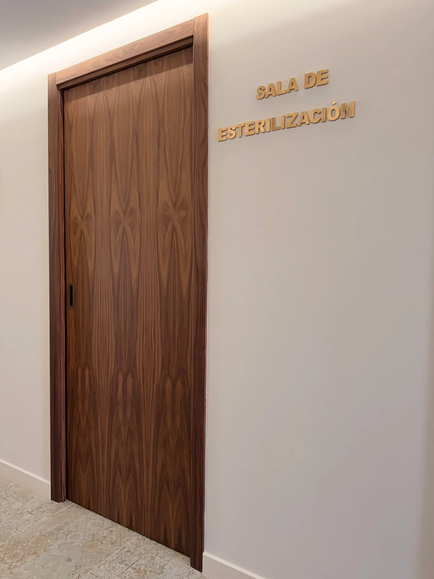 Puerta de la sala de esterilización, en madera de nogal, con el rótulo en letras doradas